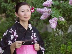 CU Shot of Mature woman in traditional Japanese clothing and smiling calling Yukata with fan / Tokyo, Japan Stock Footage