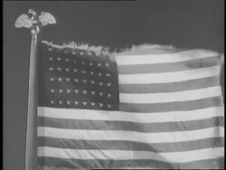 An American flag rises to the top of a flagpole on a windy day. News Clip