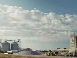 Drive-by ethanol plant in small rural town and blue sky Stock Footage
