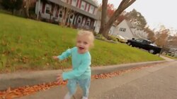 Young girl running down a street happily in suburbia, USA reaches out and touches camera Stock Footage