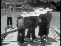 1944: CHINESE TRANSPORTATION: BOATS: Sampans docked in canal. MS Chinese men standing on boat pulling large oar. Boats filled w/ goods on waterway. Chinese man using bamboo pole to steer boat. Two sailing boats moored in canal. Instructional Video