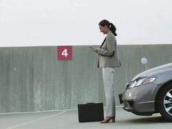Businesswoman waiting by car in car park Stock Footage