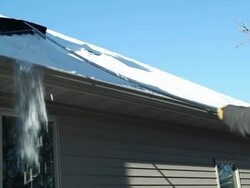 Using a Roof Rake to Remove Winter Snow Stock Footage