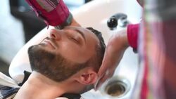 brutal hairdresser washes head of a bearded hipster Stock Footage