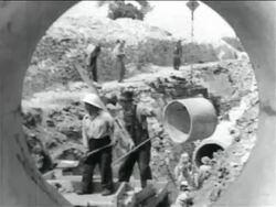 B/W 1934 view thru pipe of men working in WPA sewage construction project / documentary Stock Footage