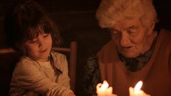 A young girl and grandmother read a book by the light of candles Stock Footage