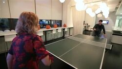 Two office workers play ping-pong game in big corporate break-room Stock Footage