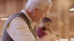 TD Senior man reading and writing notes in library Stock Footage