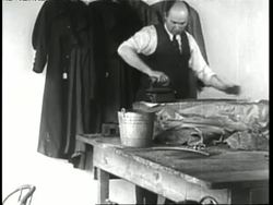 A tailor irons clothing in his laundry shop. News Clip
