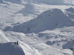 Aerial wrap of skiers on summit of large Alaskan mountian Stock Footage