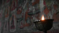 Burning oil lamp inside Thiksay Monastery and it's murals depicting life of Buddha in Ladakh, Jammu and Kashmir, India Stock Footage