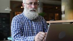 Adult senior bearded man sitting with a laptop Stock Footage