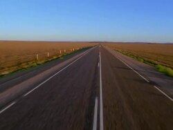 Aerial along deserted highway / up to and over man walking on highway Stock Footage