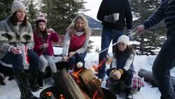 Multi-generation family toasting marshmallows over fire pit on snowy patio Stock Footage