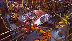 Robotic arms weld on a car as it moves down an assembly line. Stock Footage