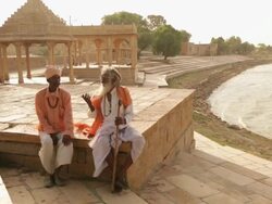 Two men talking at lakeside, Jaisalmer, Rajasthan, India Stock Footage