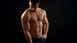 beautiful athlete trains with a dumbbell on a black background Stock Footage