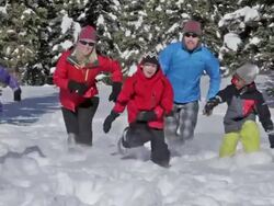 A family and dog play in the snow on a sunny, winter day Stock Footage