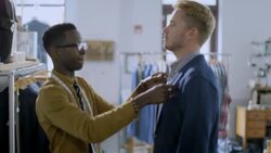 Clothing store clerk adjusts customer's jacket collar to take measurements Stock Footage