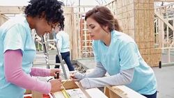 Diverse young women work together to build home for charity Stock Footage