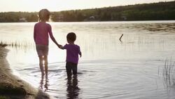 Sisters wading in the lake water at sunset Stock Footage