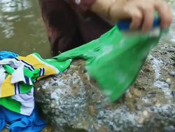 MS SLO MO Shirt being washed on rock of riverbank / Vang Vieng, Vientiane, Laos Stock Footage