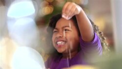 Cute young girl laughs with mom as she sprinkles flour on flattened cookie dough Stock Footage