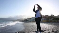 Woman takes smart phone pic on beach, sunrise Stock Footage