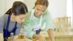 Carpentry teacher guiding student with ruler and blueprints in workshop classroom Stock Footage