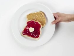 CU Woman hand entering setting down round white plate with peanut butter and strawberry jelly jam bread sandwich / Omaha, Nebraska, United States Stock Footage