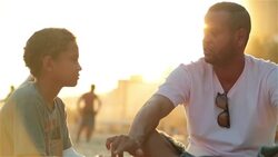 Father lectures son on sunny Brazilian beach Stock Footage