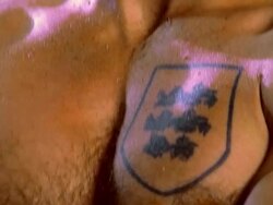 close up tilt up from tattoo of crest on man's chest to his face as he stands outdoors at night Stock Footage