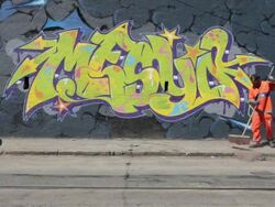 MS ZI Shot of street cleaner sweeping in front of spray painted graffiti on wall at roadside / Rio de Janeiro, Brazil Stock Footage