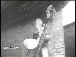 1940s: UNITED STATES NAVY:  VS Naval shipyard, officer on moving gangplank, workers on ladder cleaning or painting propeller &amp; rudder of ship, male welding metal, fitting anti-aircraft machine gun, incomplete ship nearly fully repaired in dry dock. Instructional Video