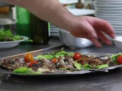 Close up shot of a chef putting fresh cherry tomatoes onto grilled lamb Stock Footage