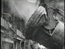 Molten metal pours out of a container and sparks fly at a factory. News Clip