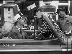 1947: STANDARD OIL (INDIANA): SERVICE STATION DRAMATIZATION:'Mr Fitzgerald' seated in driver's seat of convertible car parked in front of gas station pumps, greeted by Standard Oil attendant 'Brownie' & wash windshield, smiling. Americana, automobile Instructional Video