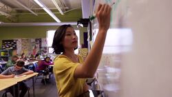 Teacher writing lesson on whiteboard for elementary students Stock Footage