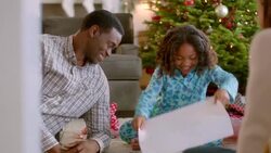 Thankful young girl opens Christmas present, admires her new pink sweater, and hugs her father (dolly-shot) Stock Footage