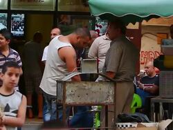 Man cooks meat, smokes, other men and boys in Tripoli, Lebanon Stock Footage