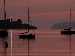 WS Sailboats floating on bay of port in front of lighthouse / Mallorca, Balearic Islands, Spain Stock Footage