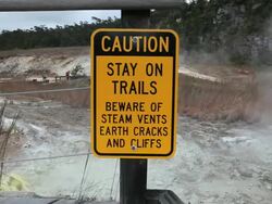 MS Shot of caution sign at Sulphur Banks with steam and suplur banks in distance in Volcanoes National Park / Volcano, Hawall, Big Island, United States  Stock Footage
