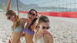 Playful young women at beach volleyball net Stock Footage