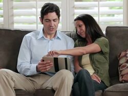 MS Couple sitting on sofa and browsing on tablet computer / Portland, Oregon, United States Stock Footage