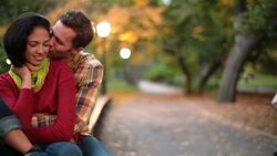 New York couple in love nuzzle on park-bench in Central Park, boyfriend kisses girl on cheek (dolly-shot) Stock Footage