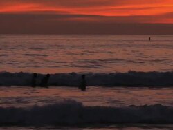 Boys play and jump in ocean waves at sunset Stock Footage