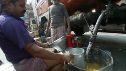 A vendor fills cans of cooking oil from a tanker truck. Stock Footage