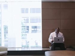  WS Businessman typing on laptop computer in reception area / Seattle, Washington, United States Stock Footage