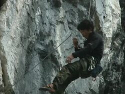 A Japanese rock climber descending and removing climbing gear Stock Footage