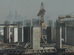 MS Two yellow cranes sit in the middle of a high-rise construction site with Men work between the concrete columns / Doha, Qatar Stock Footage
